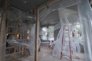 Wrapping around a red brick chimney and weaving through bare stud walls, inflated tubes of transparent plastic fill the space of a house under construction.