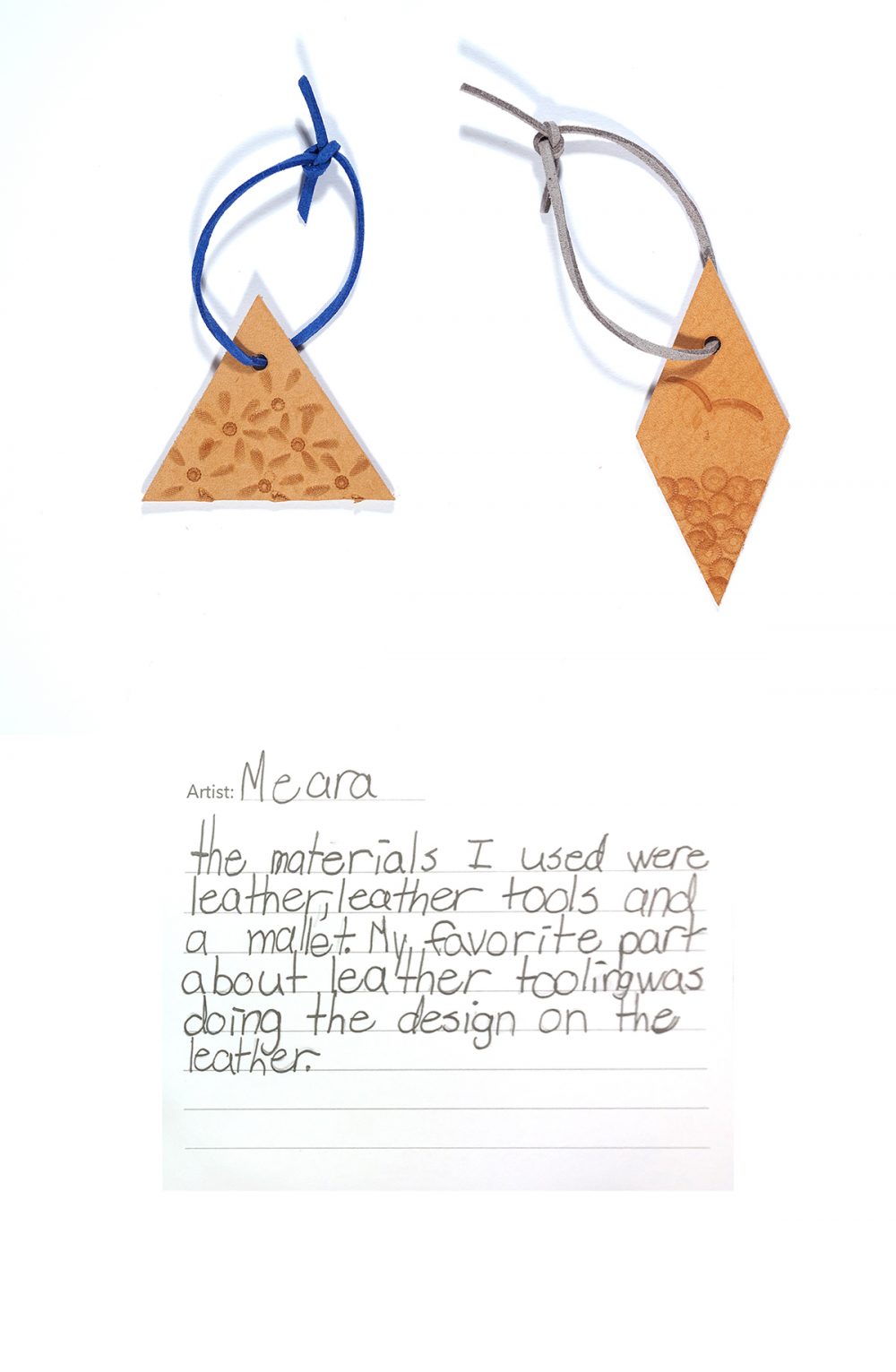 Two leather shapes, one a triangle and the other a diamond, are stamped with patterns. Both are punched with a single hole that has been treaded with a leather lace tied in a loop at the top. Below handwritten text reads "Artist: Meara", "The materials I used were leather, leather tools and a mallet. My favourite part about leather tooling was doing the design on the leather."