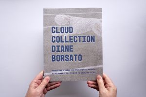 Two hands hold the cover of a Cloud Collection with "CLOUD COLLECTION DIANE BORSATO" in large uppercase blue type.