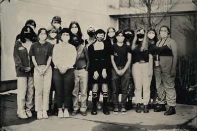 In this black and white photo, the group of graduating Fine Art students stand outside of a building.